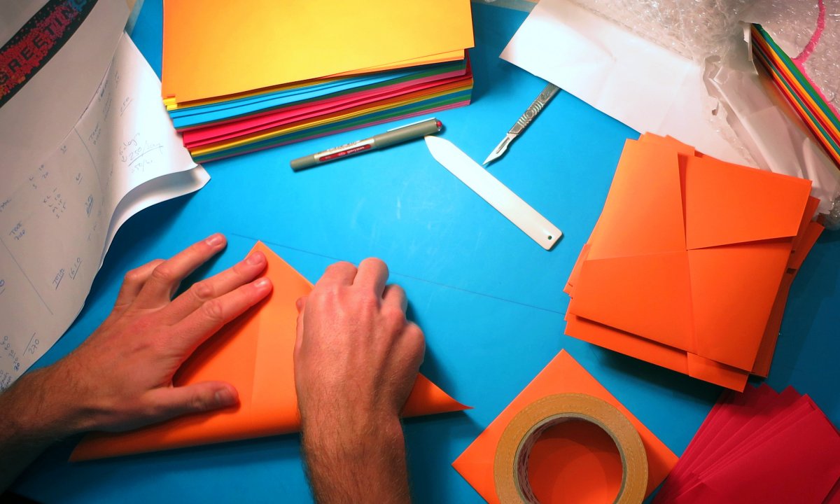Folding of coloured papers in readiness for new Nabarro's canteen wall display by Neon Design & Branding Consultancy www.neon-creative.com